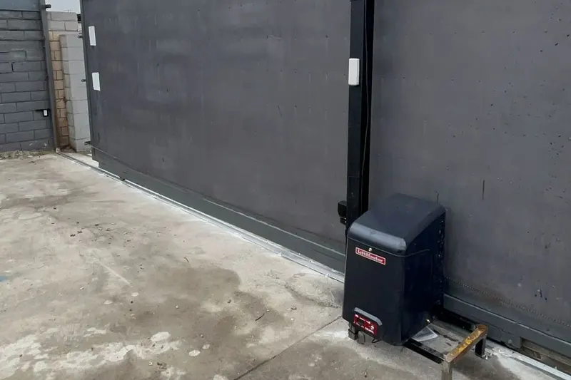 A gate operator and its control enclosure mounted beside a driveway gate