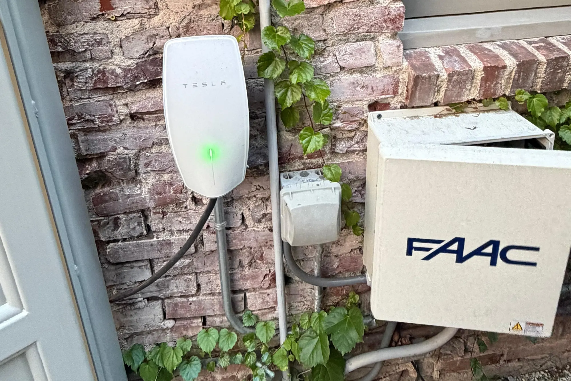 A FAAC swing gate operator arm connected to a metal driveway gate post