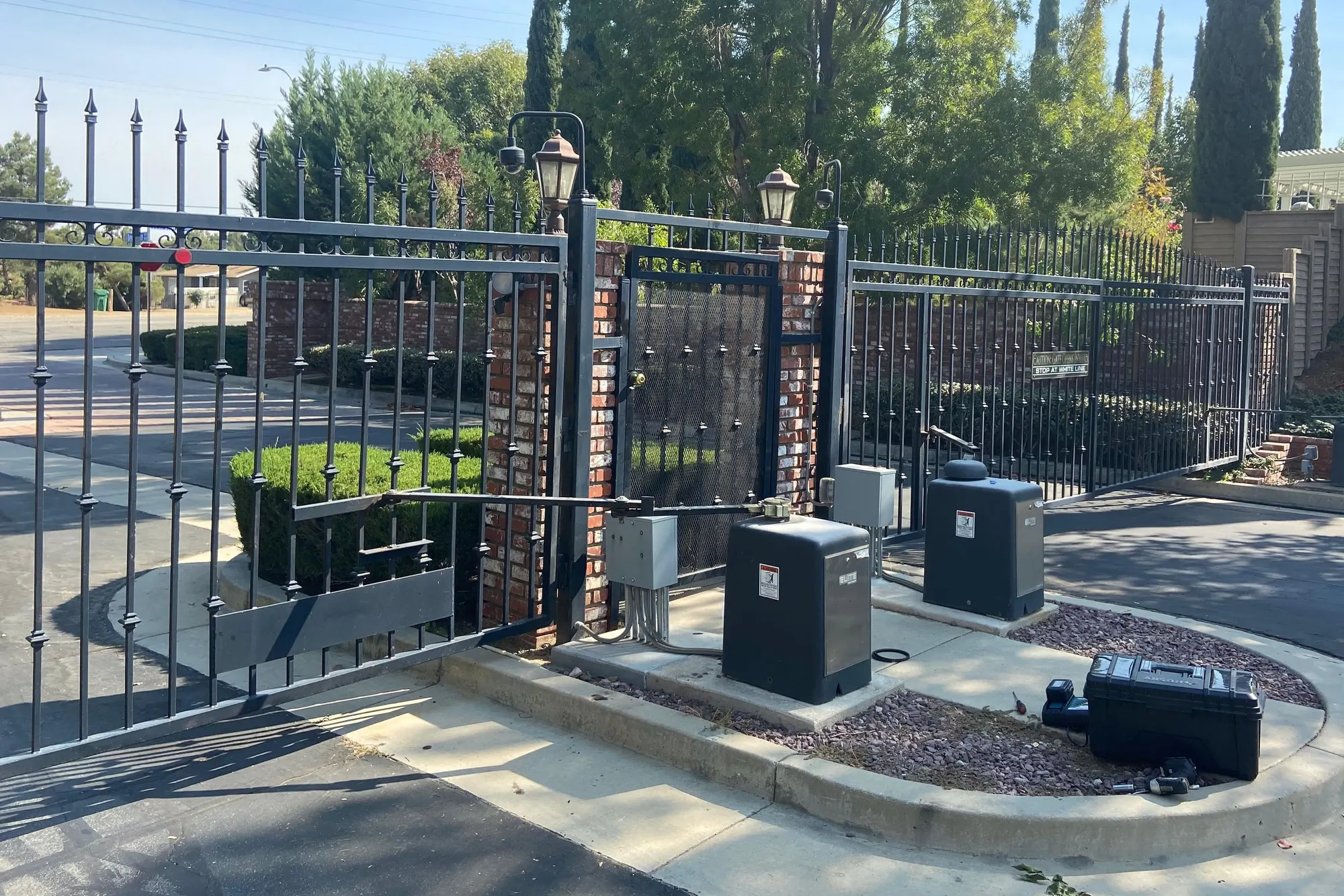 A pair of metal driveway gates hung on new posts, partly open
