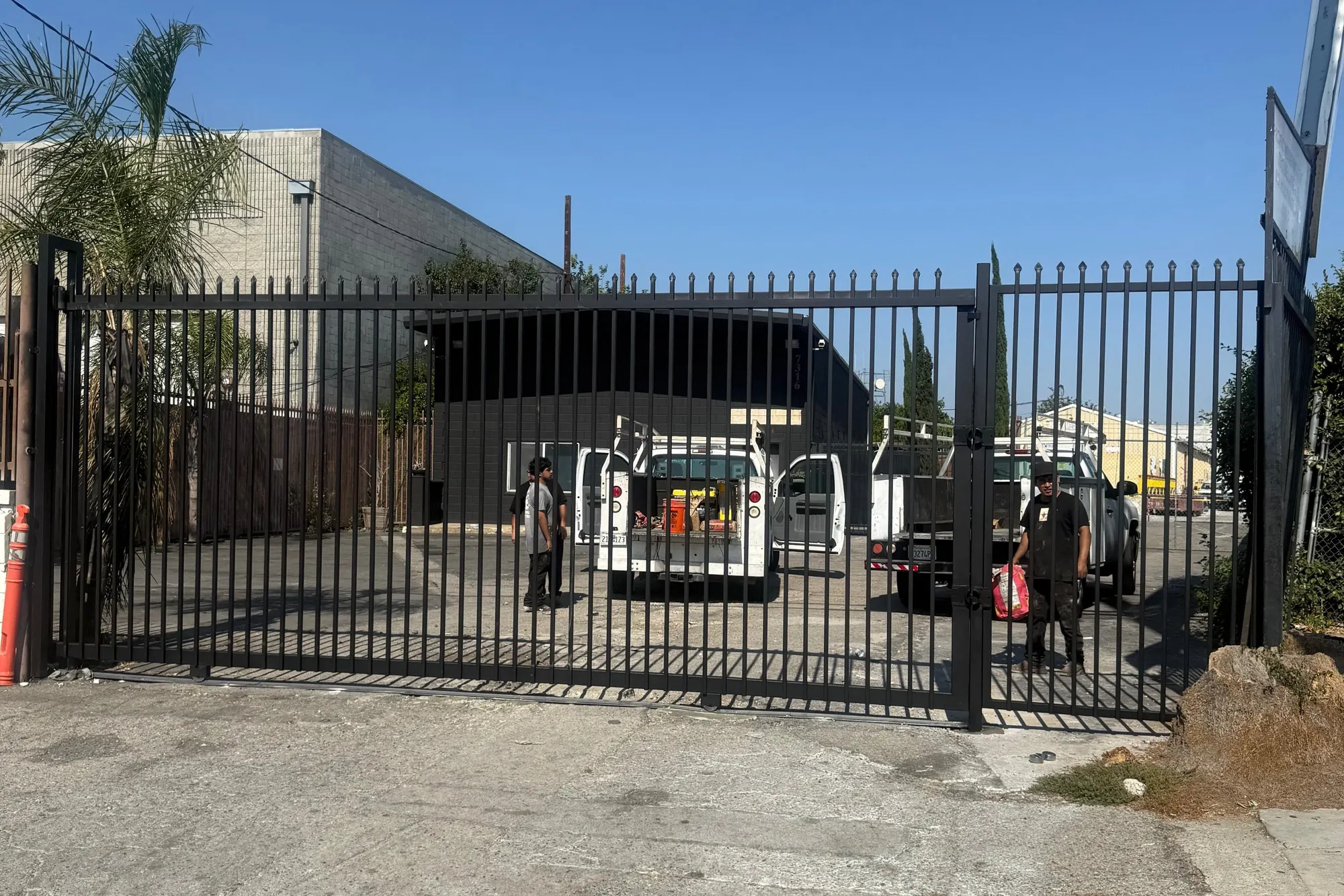 An ornamental iron driveway gate installed between masonry pillars