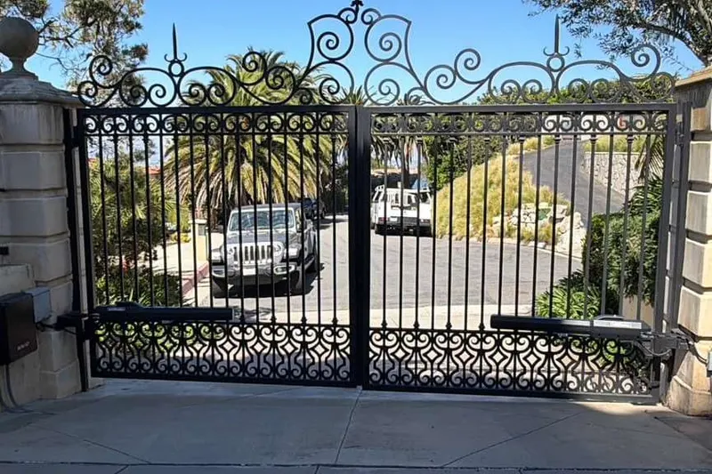 An ornamental iron pedestrian gate alongside a larger driveway gate