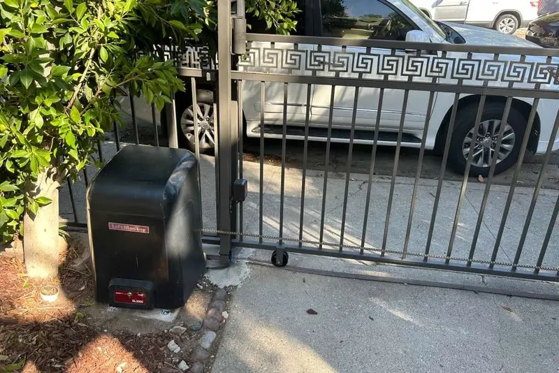 A LiftMaster SL3000 slide operator installed at the edge of a driveway, with the gate rolled back on its track