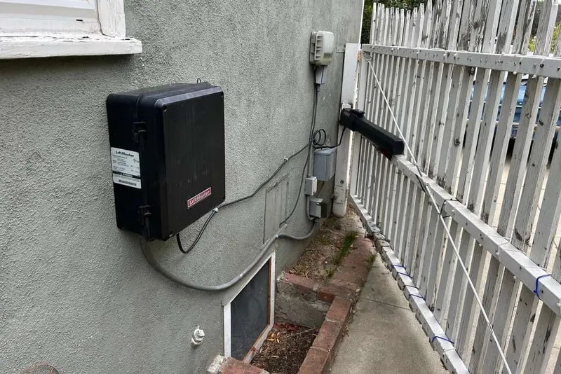 A LiftMaster swing gate operator arm connected to a wrought iron gate leaf