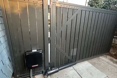 A LiftMaster operator mounted beside a decorative iron gate at a residential driveway entrance